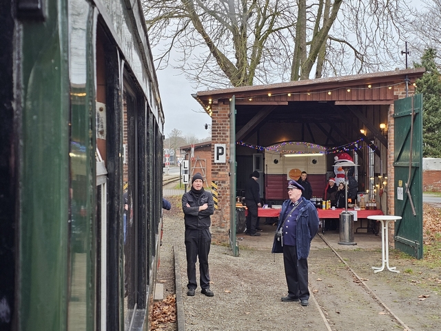 Abb.: Im Asendorfer Lokschuppen gibt es an allen vier Adventswochenenden Bockwurst und Getränke in Zusammenarbeit mit Asendorfer Schulen sowie leckere Waffeln vom DEV. Lokführer Florian Jülke und Schaffner Volker Hoppmann warten auf die Abfahrt, während die Fahrgäste es sich wieder im muckelig warmen Zug gemütlich gemacht haben.